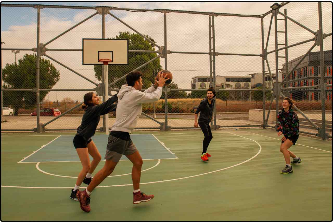 Group of friends playing basketball on an outdoor court.